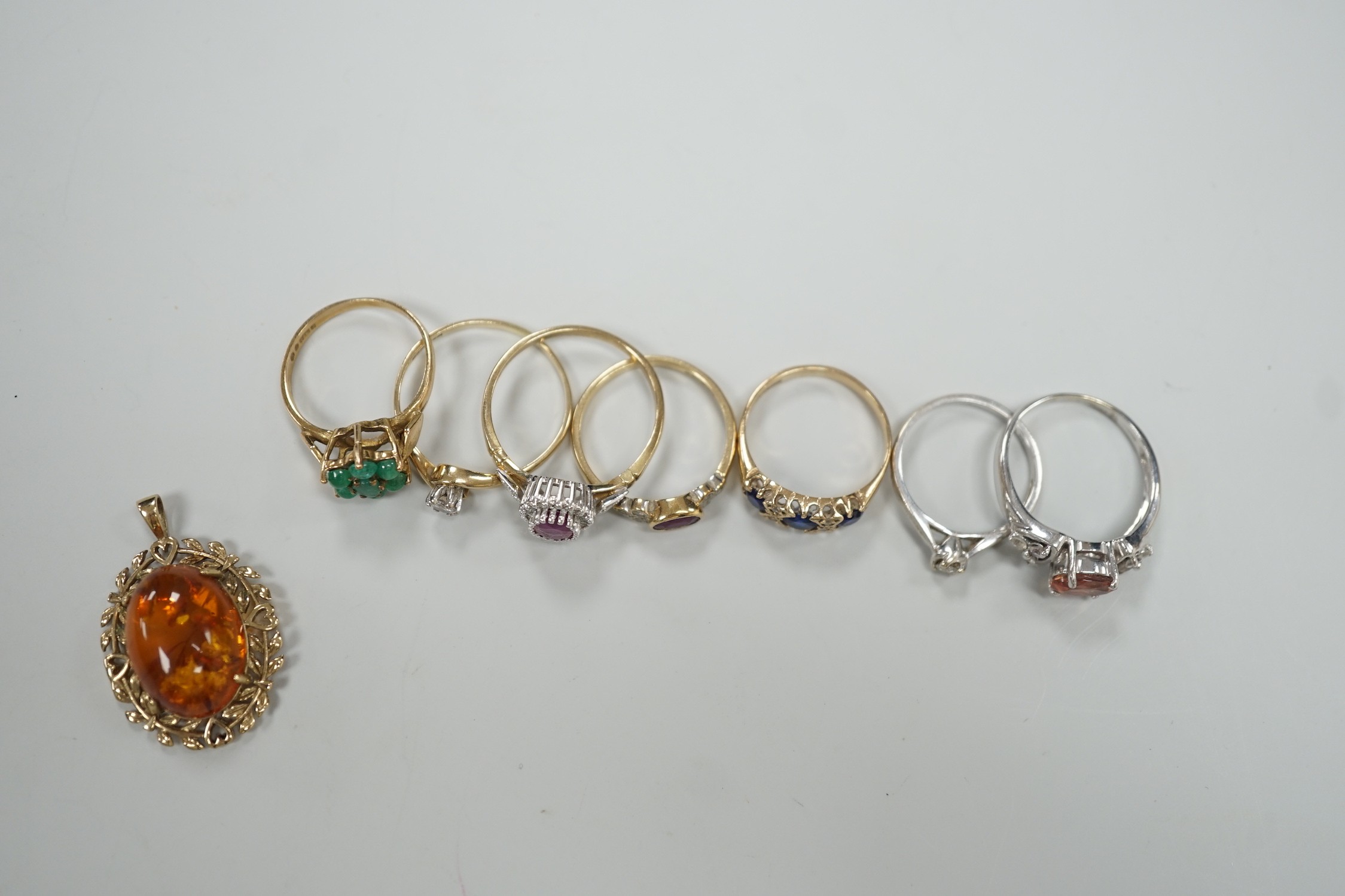 Seven assorted modern 9ct gold and gem set rings, including two solitaire diamond rings, together with a 9ct gold and amber set pendant, gross weight 19.3 grams.